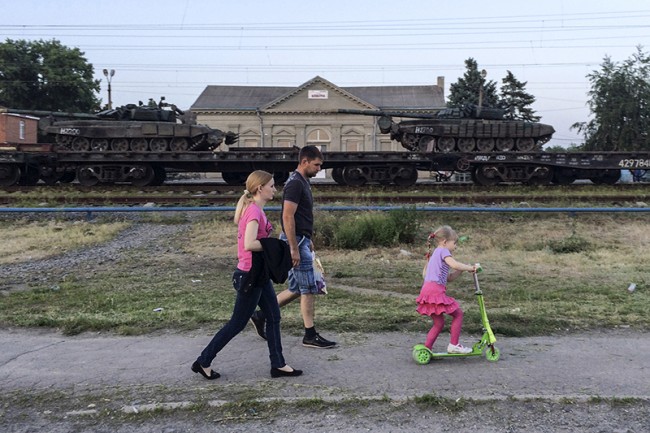 Tanks are seen on a freight train shortly after its arrival at a railway station, with people walking in the foreground, in the Russian southern town of Matveev Kurgan, near the Russian-Ukrainian border in Rostov region, Russia, May 26, 2015. Picture taken with a mobile phone. REUTERS/Maria Tsvetkova - RTX1EN0H