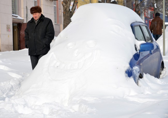 A man walks past a car covered with snow after a heavy snow storm hit the Ukrainian capital of Kiev on March 24, 2013. Kiev administration declared a state of emergency in the city and announced that residents could take the day off tomorrow following three days of heavy snowfalls.  AFP PHOTO/SERGEI SUPINSKY        (Photo credit should read SERGEI SUPINSKY/AFP/Getty Images)