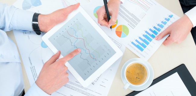 Business team analyzing income charts and graphs with modern digital tablet. Top view photoshoot.