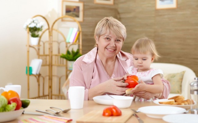 Бабушка кормит маленькую внучку